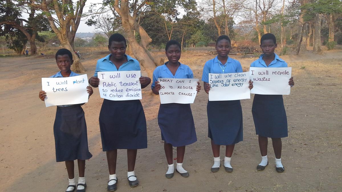 Students at Lilongwe Girls’ Secondary School in Malawi hold up signs showing the ways in which they can help to slow global warming (Photo: UNITAR)