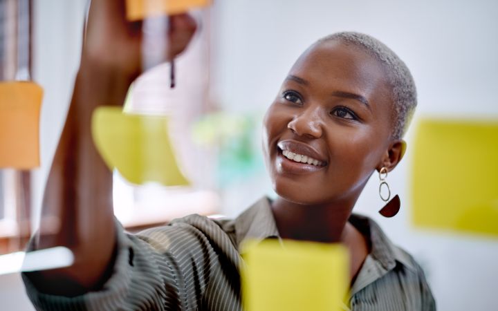 Explore your Transformative Potential (Photo via Envato Elements) Woman is writing a note on a glass board with notepads