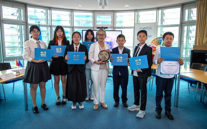 Youth Leadership and Global Challenges Seminar: Students received certificates of completion, presented by Director of Division for Prosperity Mihoko Kumamoto (centre) In an airy meeting room, four Chinese girls and three boys in school uniforms flank an East Asian senior professional. The students hold up their certificates for the camera.