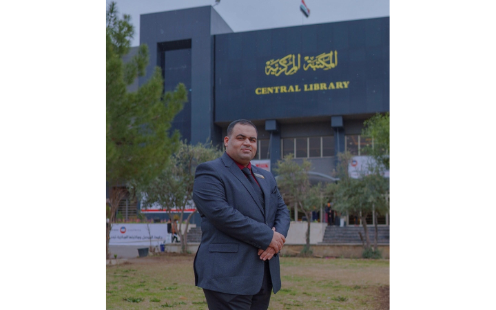 Sayf, Secretary General of the Libraries (Director of the Central Library) at the University of Mosul Sayf poses for a photo, Central Library in the background