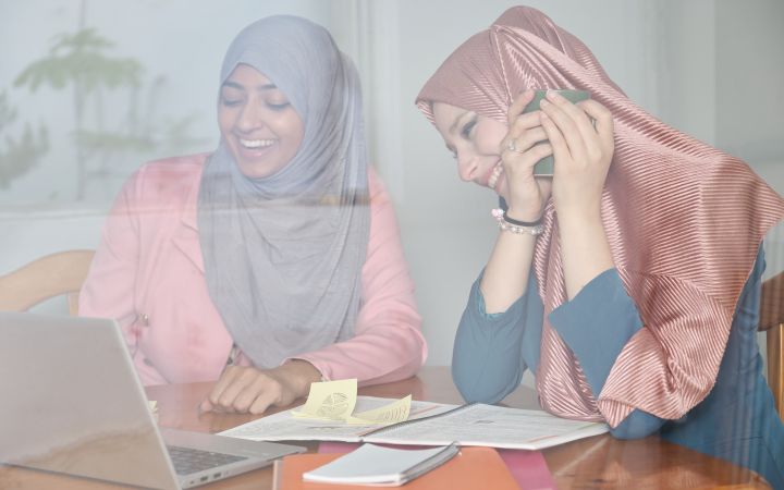 Two women smiling while looking at the laptop