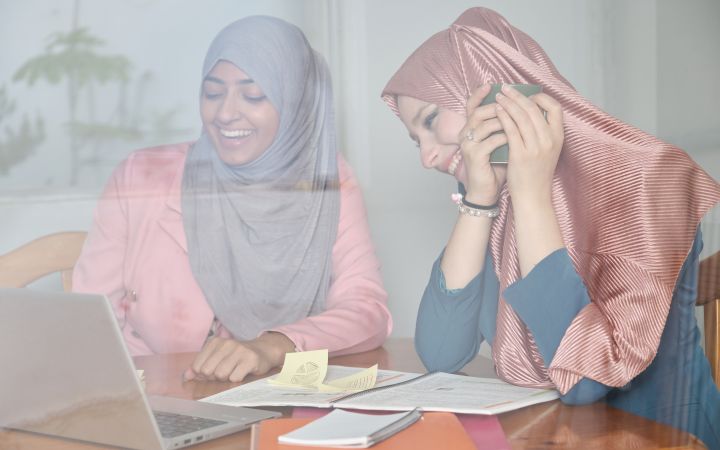 Two women smiling while looking at the laptop